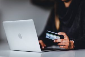 A woman holding a credit card while browsing her computer - Darren Yaw Latest News